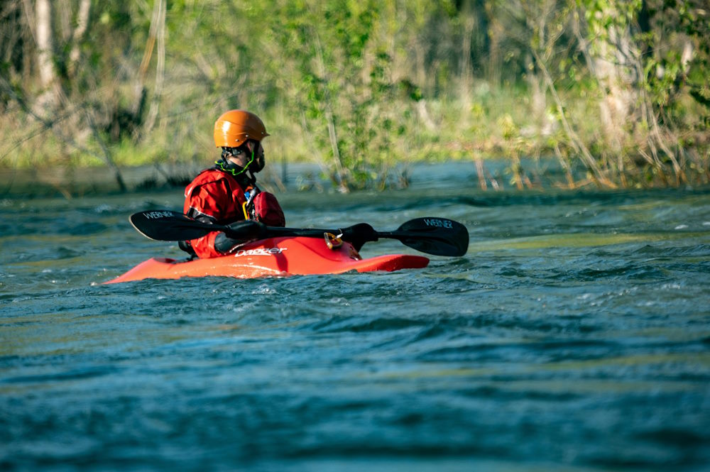 A man on red kayak floating down The Delaware water gap. 